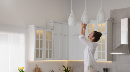 Woman adjusting light fixture in kitchen