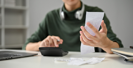 Person sitting at table and working with calculator and receipts